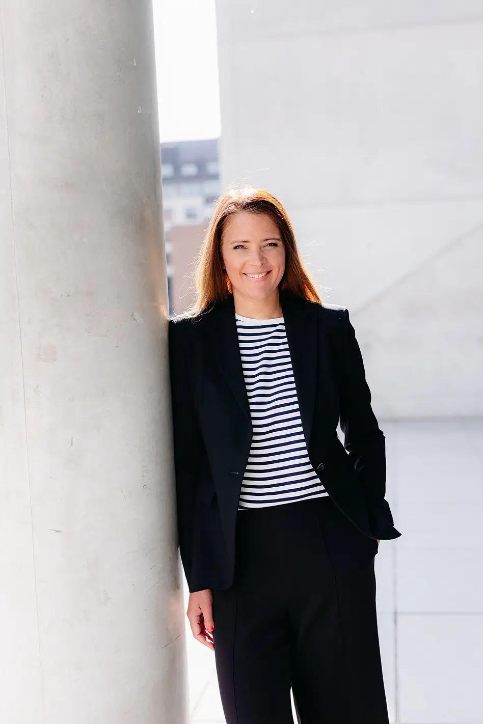 Businessporträt einer Unternehmerin im schwarzen Blazer vor moderner Architektur in München – authentische Personal-Branding-Fotografie