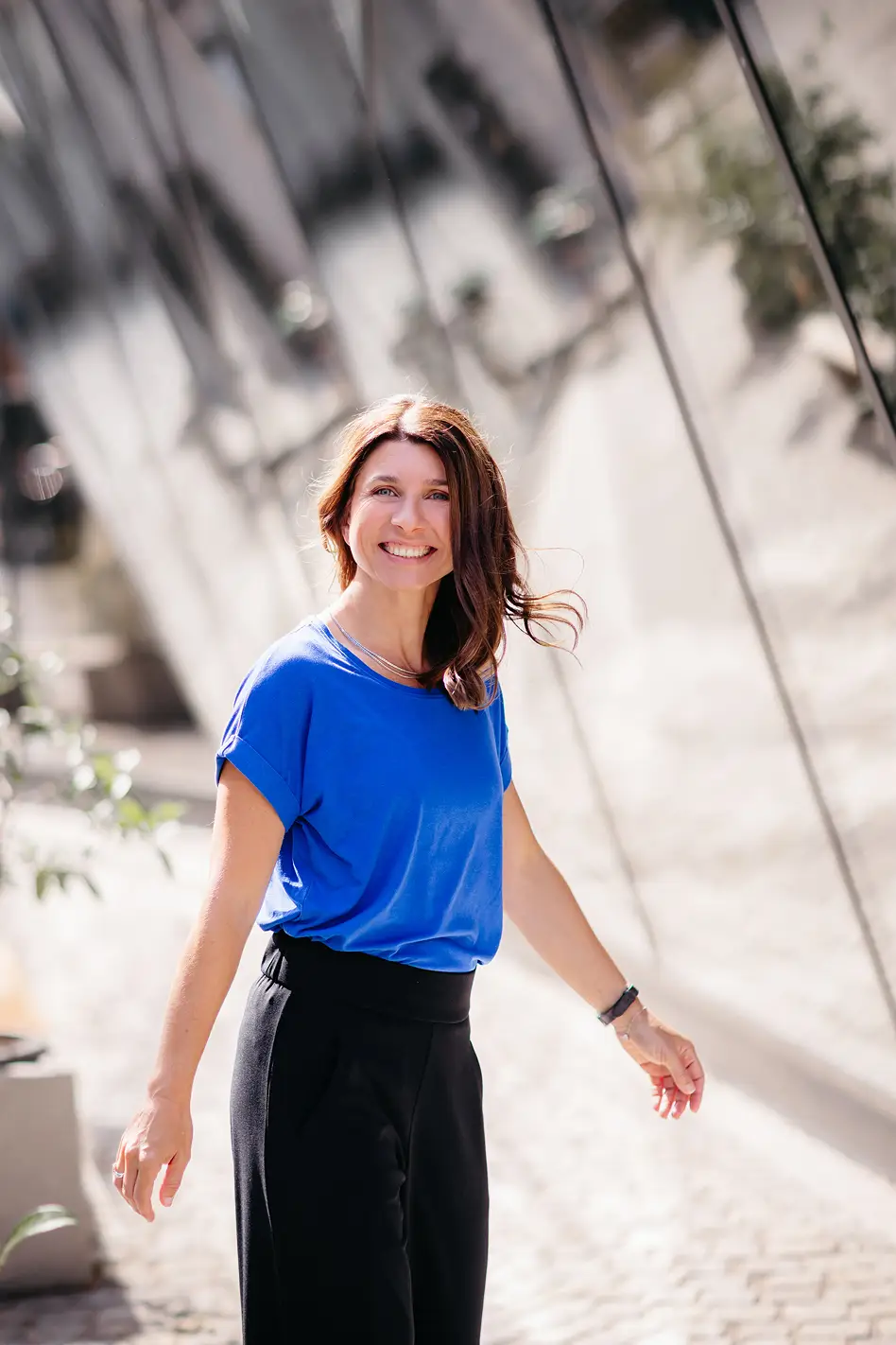 Personal Branding Fotografie einer Unternehmerin im Gehen mit offenem Lächeln in natürlicher Umgebung